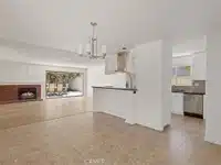 dining and living area with white walls, chandelier and fireplace in California.
