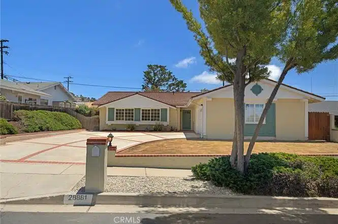 Front view single-story house with white siding and red-tiled roof in California.