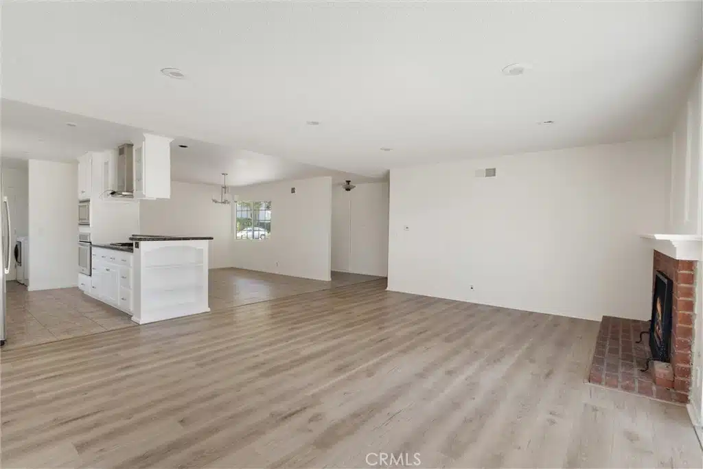 room with wood flooring, white kitchen and a fireplace in Calfornia.