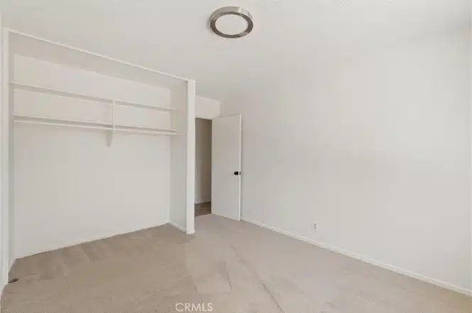 Empty room with carpet, white cabinet and an open door in California.