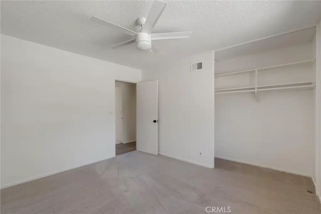 Empty room with carpets, white walls and ceiling fan in California.