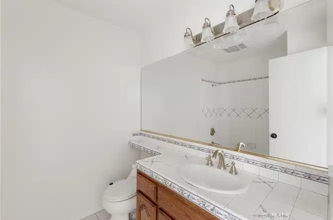 Bathroom with large mirror, and a tiled countertop in California.