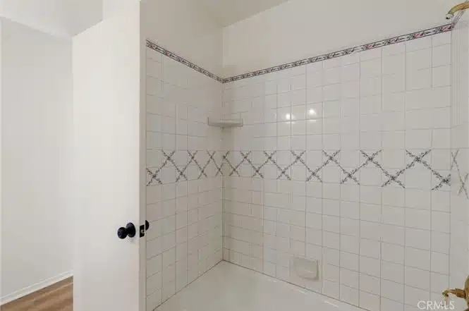 Tiled shower with a patterned horizontal stripe in California.