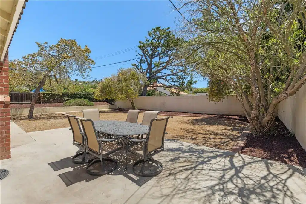 backyard patio with a metal table and tree in California.